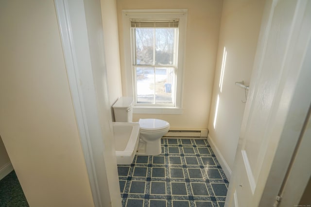 bathroom featuring a healthy amount of sunlight, toilet, and a baseboard heating unit