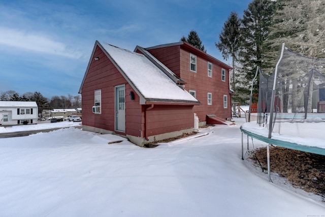 snow covered property featuring cooling unit and a trampoline