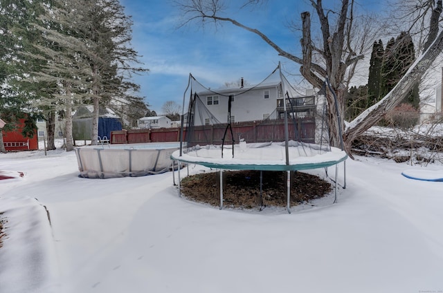 yard layered in snow with a trampoline