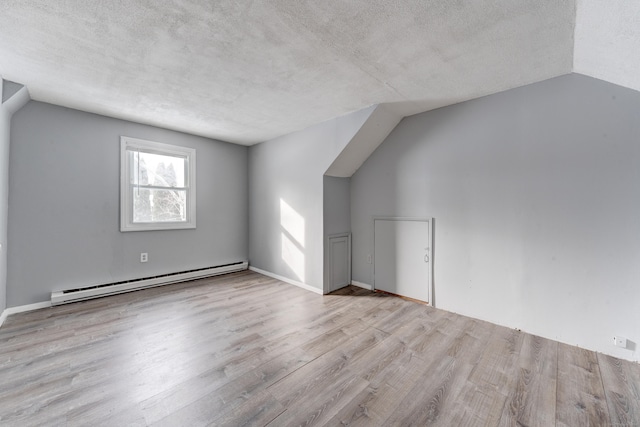 bonus room featuring lofted ceiling, a textured ceiling, baseboard heating, and light hardwood / wood-style flooring