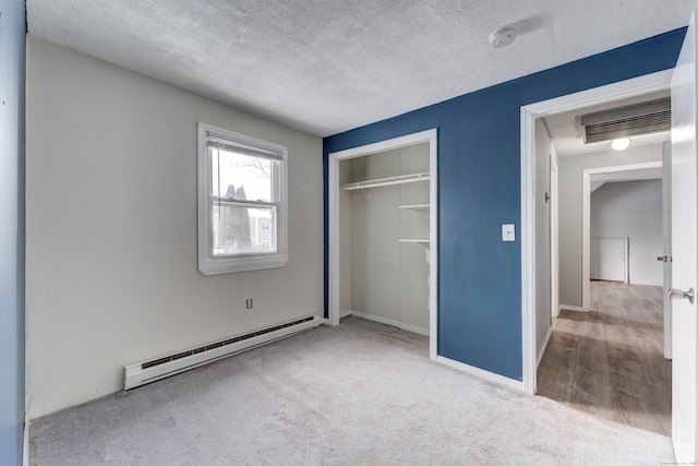 unfurnished bedroom with light colored carpet, a textured ceiling, baseboard heating, and a closet