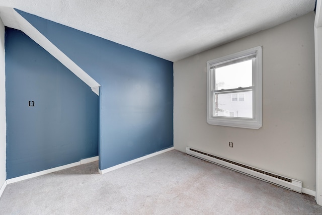 spare room with a baseboard radiator, light carpet, and a textured ceiling