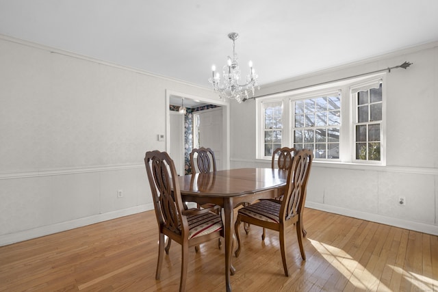 dining room with wood-type flooring, ornamental molding, and an inviting chandelier