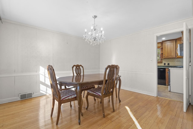 dining space with a notable chandelier, crown molding, and light hardwood / wood-style flooring