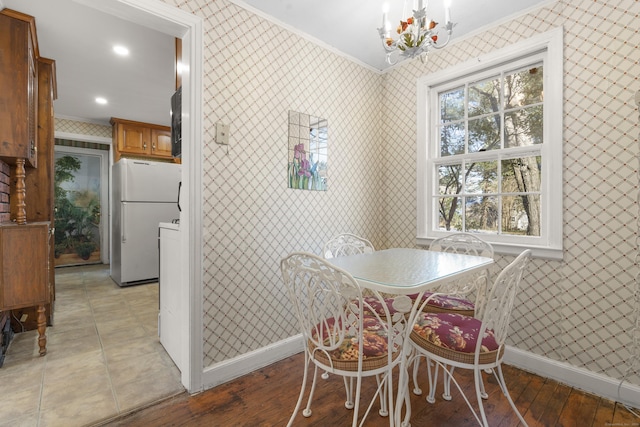 dining space featuring crown molding, a chandelier, and light hardwood / wood-style flooring