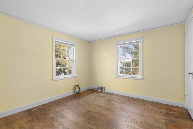 spare room featuring crown molding, plenty of natural light, and dark hardwood / wood-style floors