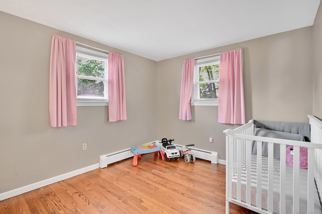 4 Sparkle St, Enfield, CT 06082 - bedroom featuring wood finished floors, baseboards, a baseboard radiator, and a crib