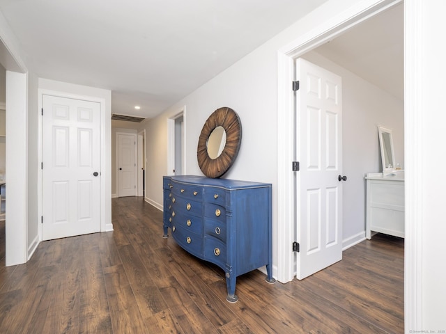 hall with visible vents, baseboards, and dark wood-type flooring