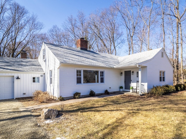 view of front facade featuring roof with shingles, a chimney, an attached garage, board and batten siding, and a front lawn