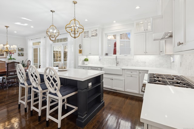 kitchen featuring sink, hanging light fixtures, white cabinets, and a kitchen island