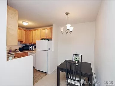 kitchen with pendant lighting, white appliances, a chandelier, and light brown cabinets