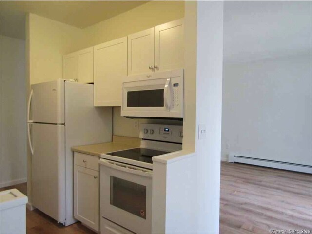 kitchen featuring white cabinetry, a baseboard heating unit, white appliances, and light wood-type flooring