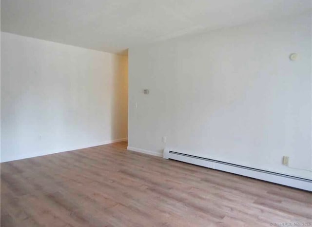 empty room with a baseboard radiator and light hardwood / wood-style floors