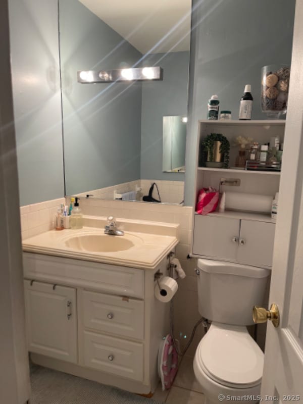 bathroom featuring tile walls, vanity, tile patterned floors, and toilet