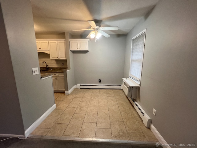 kitchen with sink, ceiling fan, baseboard heating, backsplash, and white cabinets