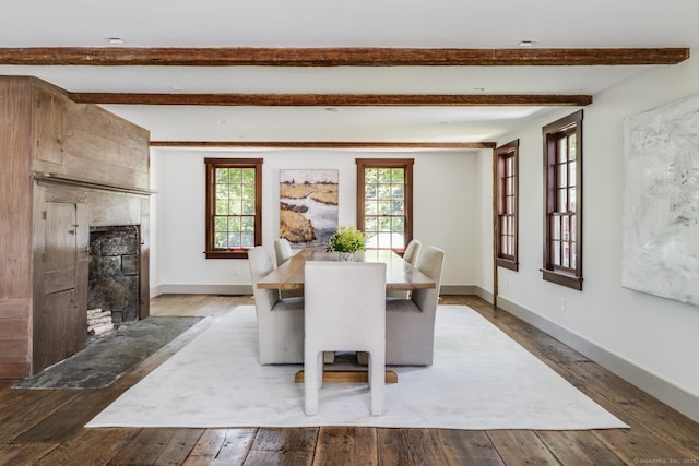 dining area featuring hardwood / wood-style flooring, a large fireplace, and beam ceiling