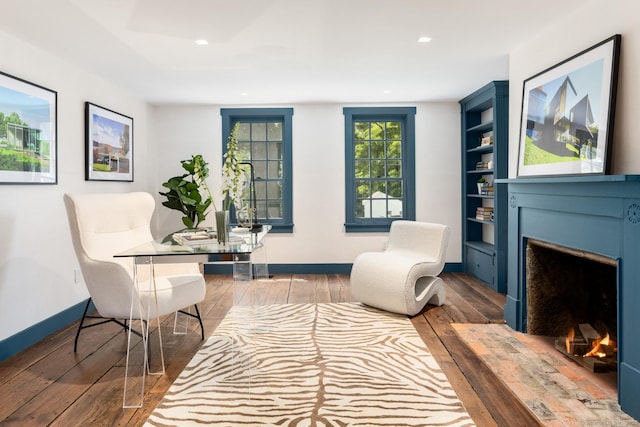 sitting room featuring hardwood / wood-style flooring and built in shelves