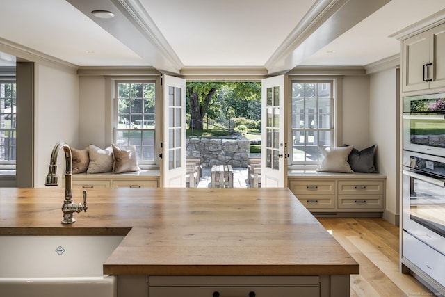 interior space featuring crown molding, sink, light hardwood / wood-style floors, and french doors