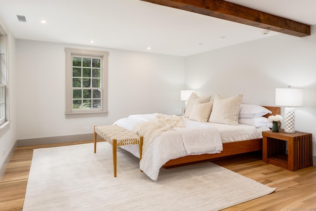 bedroom with beam ceiling and light wood-type flooring