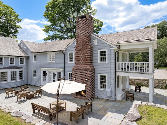 back of house with french doors, a balcony, an outdoor hangout area, and a patio