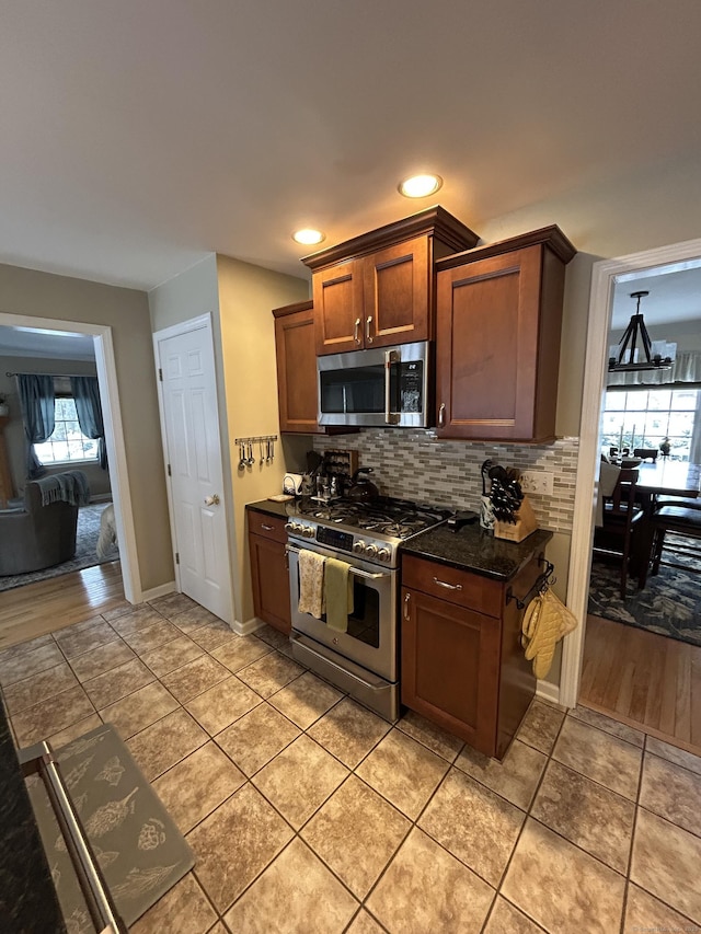 kitchen with stainless steel appliances, tasteful backsplash, light tile patterned floors, and dark stone counters