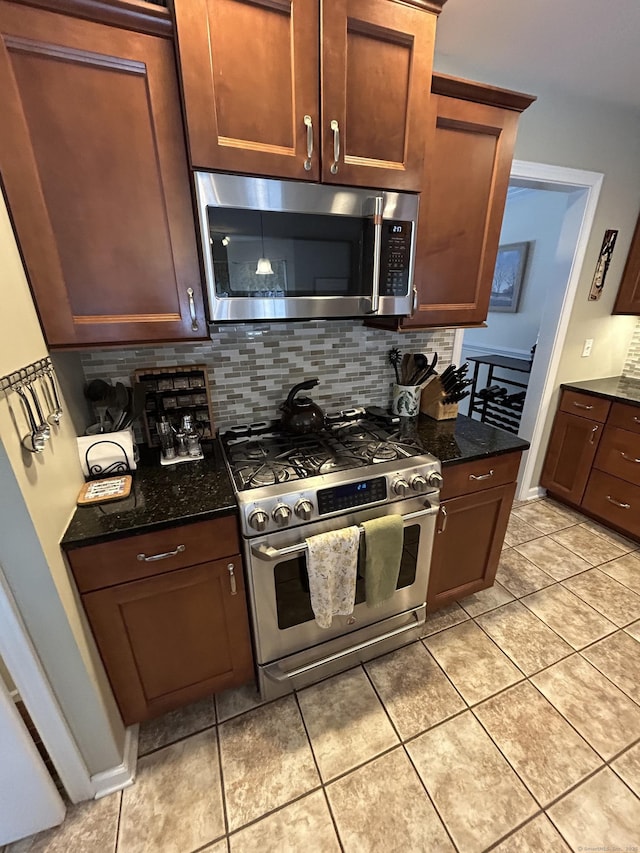 kitchen featuring tasteful backsplash, light tile patterned floors, stainless steel appliances, and dark stone counters