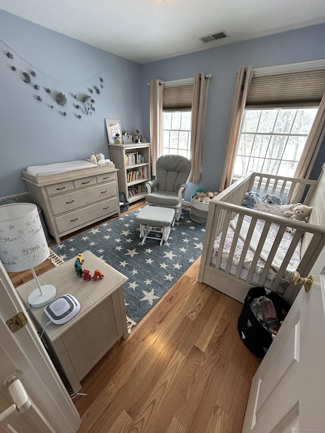 bedroom with light hardwood / wood-style flooring and a crib