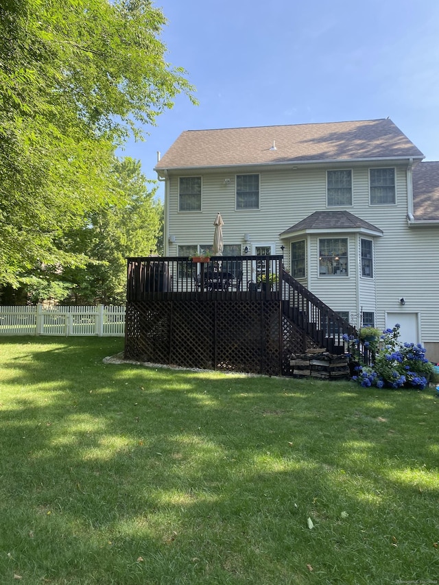 back of property featuring a wooden deck and a yard