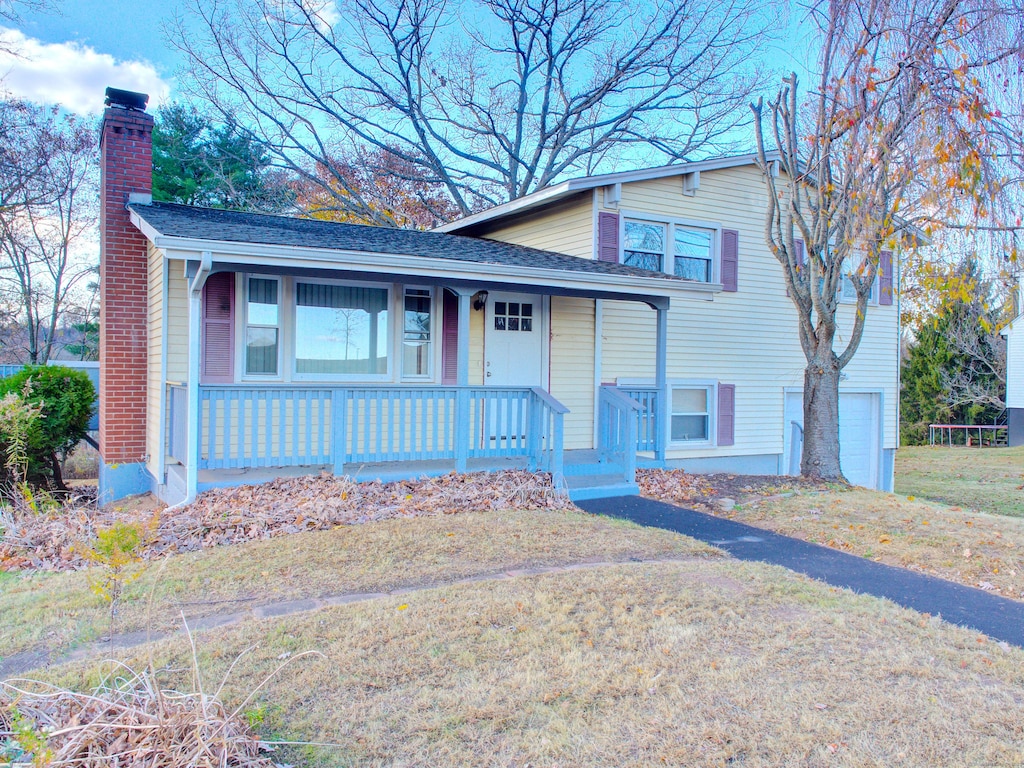 view of front of property with a garage, a porch, and a front lawn