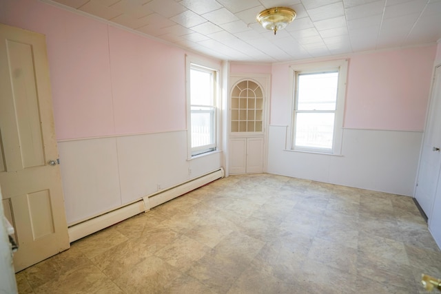 spare room featuring baseboard heating and crown molding