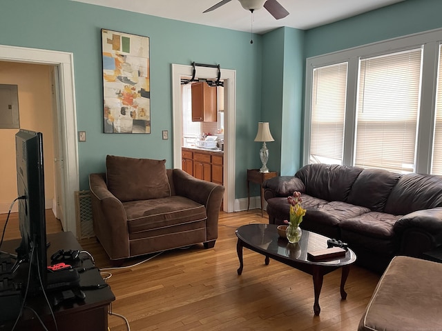 living room featuring light wood-type flooring, ceiling fan, electric panel, and plenty of natural light