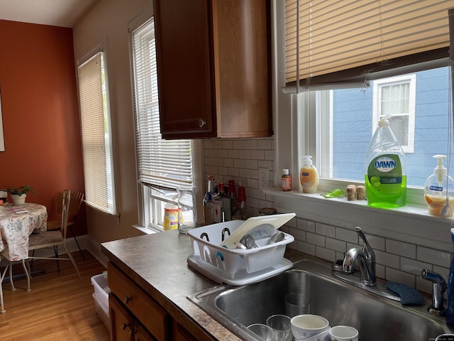 kitchen with sink, backsplash, and light wood-type flooring