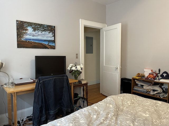 bedroom with electric panel and hardwood / wood-style floors