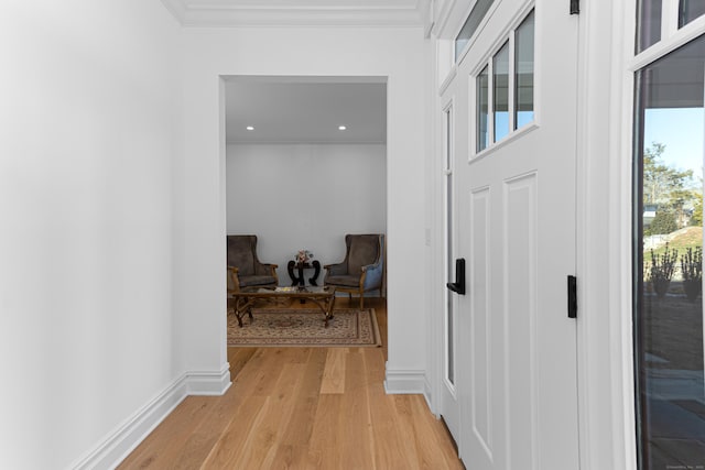 corridor with ornamental molding and light hardwood / wood-style floors