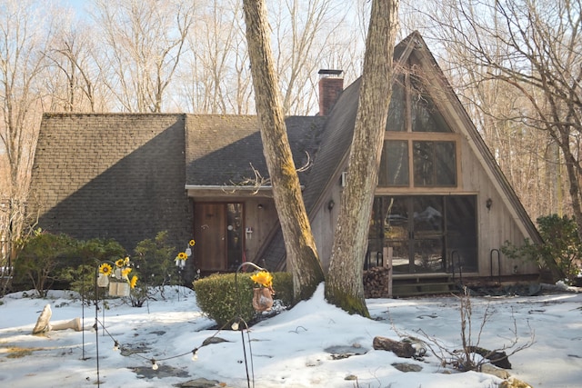 view of front facade with a shingled roof and a chimney