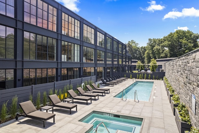 community pool featuring a patio, fence, and a hot tub