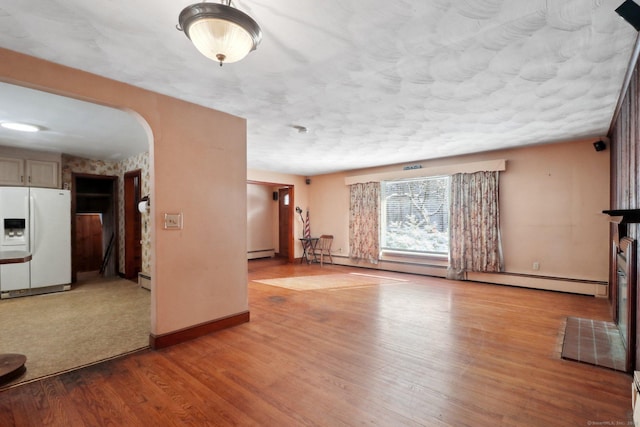 unfurnished living room with light wood-type flooring and a baseboard heating unit