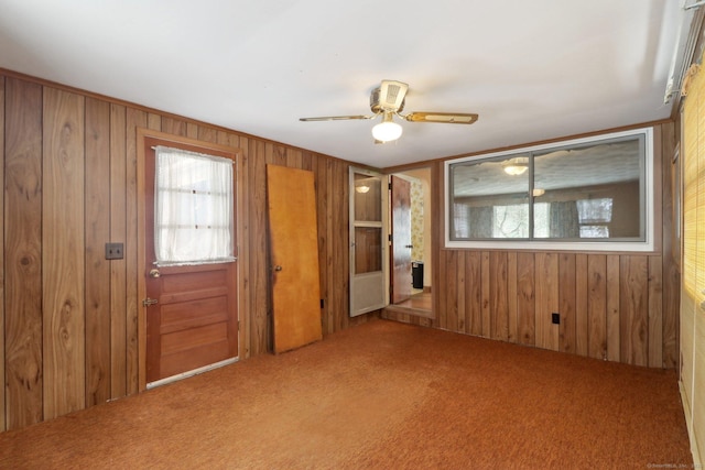 carpeted empty room with ceiling fan and wooden walls