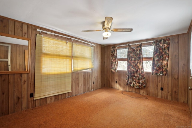 carpeted spare room with ceiling fan and wooden walls