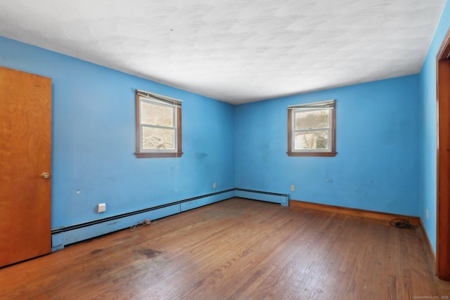 unfurnished room featuring hardwood / wood-style flooring and baseboard heating