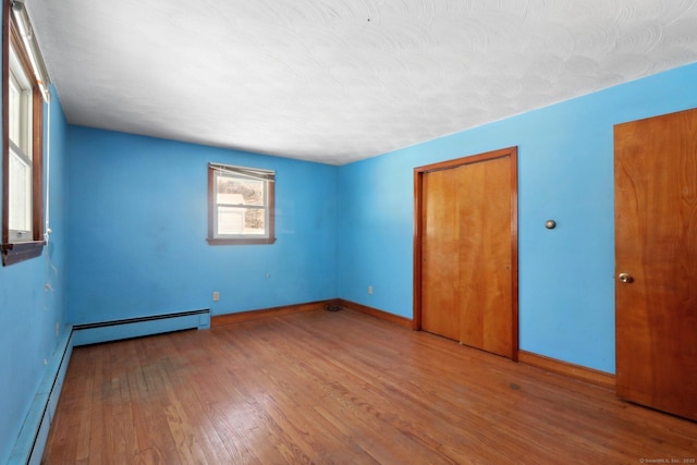 spare room with a baseboard heating unit and wood-type flooring