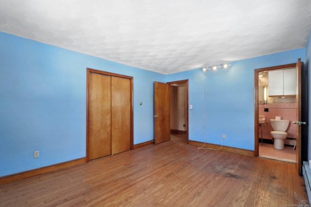 unfurnished bedroom featuring light hardwood / wood-style floors, a closet, and ensuite bath