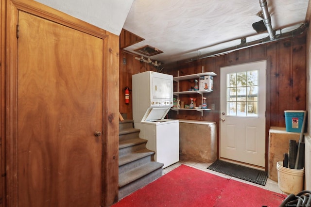 basement with wooden walls and stacked washer and dryer