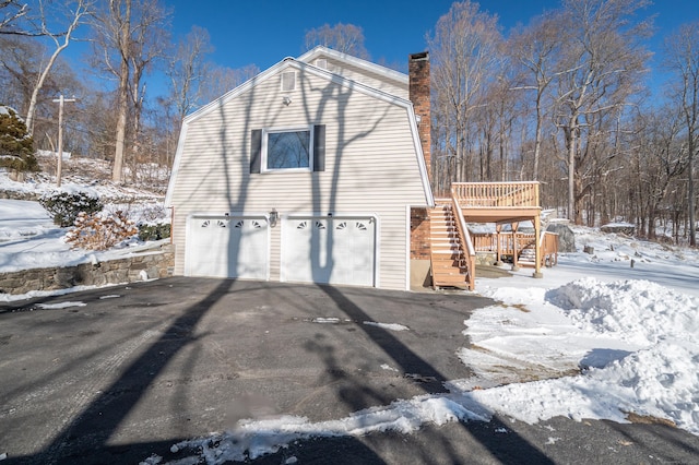 snow covered property featuring a garage and a deck