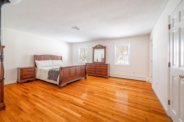 bedroom with light hardwood / wood-style flooring, a textured ceiling, and baseboard heating