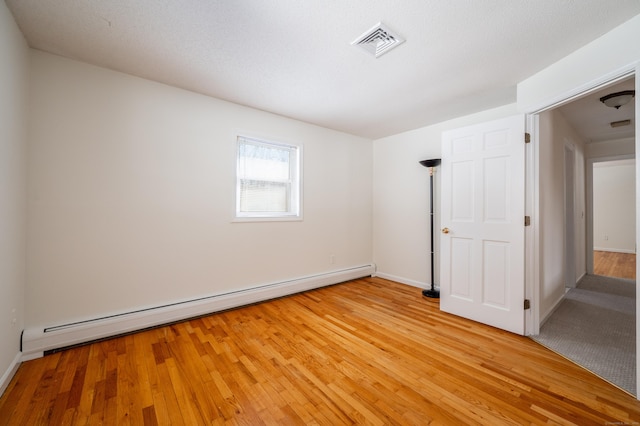 unfurnished room featuring a baseboard radiator and light wood-type flooring