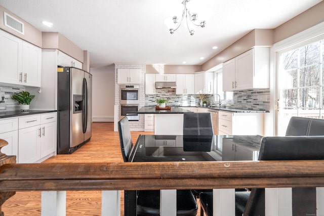 kitchen featuring sink, white cabinetry, stainless steel appliances, light hardwood / wood-style floors, and decorative backsplash