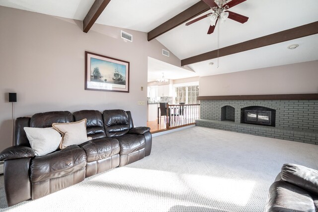 carpeted living room with lofted ceiling with beams, a brick fireplace, and ceiling fan with notable chandelier