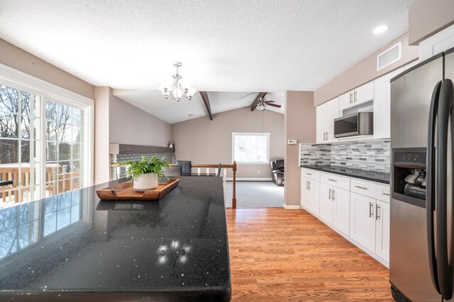 kitchen with lofted ceiling, white cabinetry, baseboard heating, stainless steel appliances, and light hardwood / wood-style floors