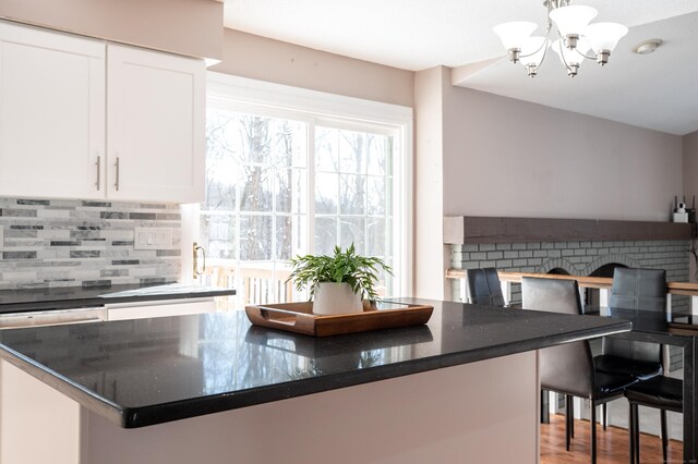 kitchen featuring white cabinets, a chandelier, backsplash, hanging light fixtures, and light hardwood / wood-style flooring